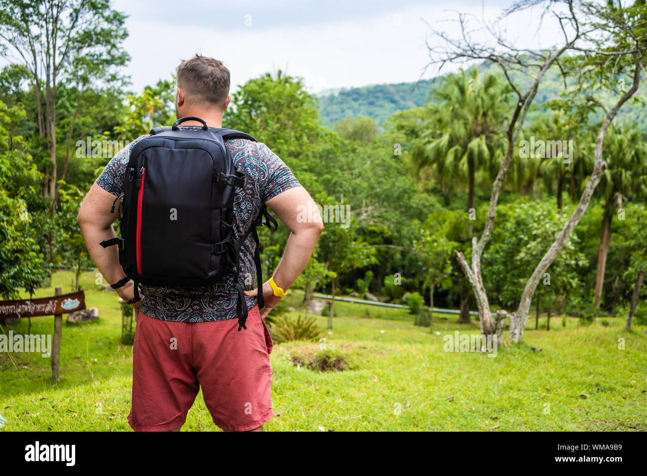 Schönen tropischen Wald mit einem Reisenden jungen Mann mit einem Rucksack  auf dem Weg nach Thailand. Ein Mann auf einer tropischen Straße und  geniesst die Aussicht Stockfotografie - Alamy