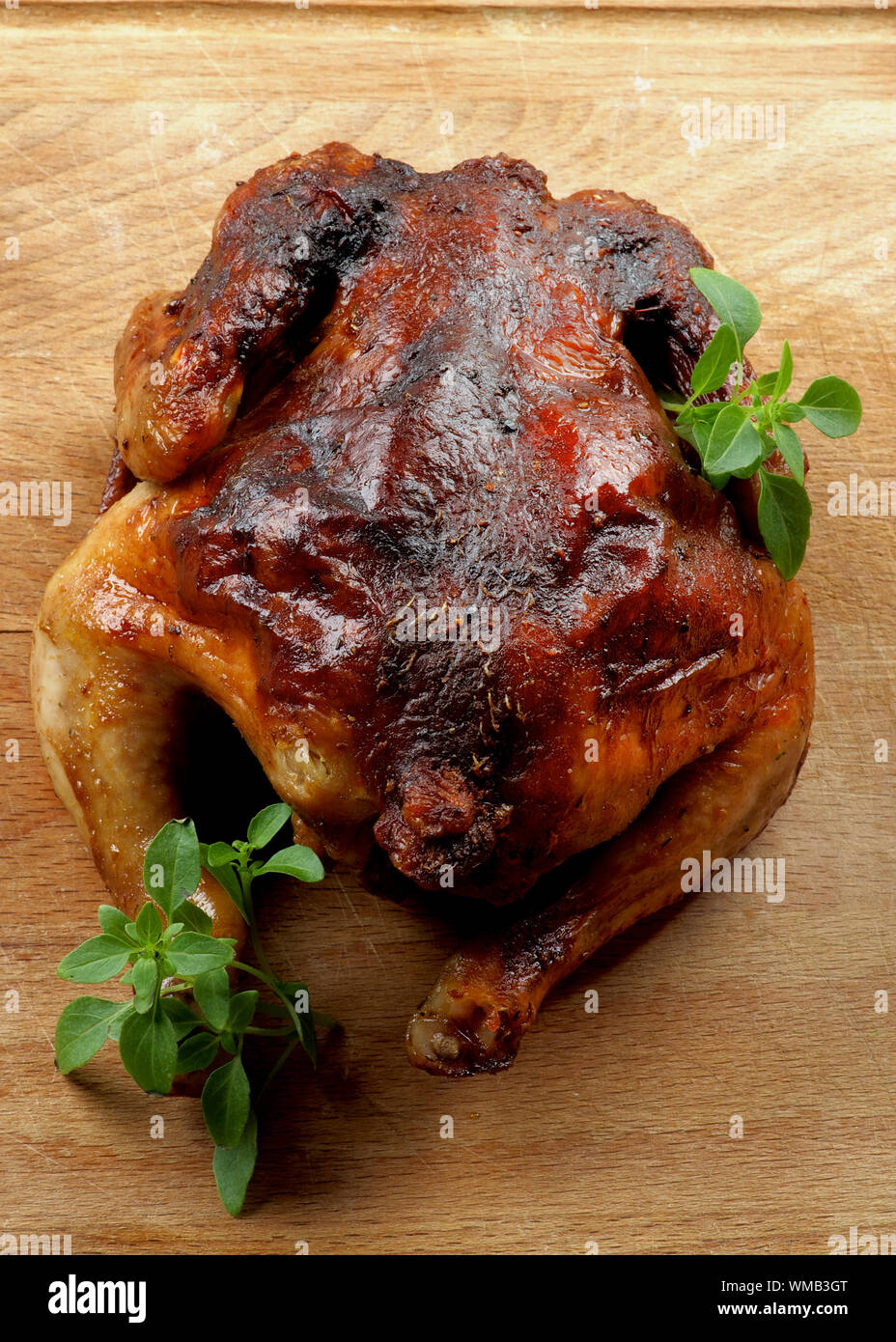 Ganzen gebratene Hähnchen mit frischem Basilikum Blätter closeup auf Holz Schneidebrett Stockfoto