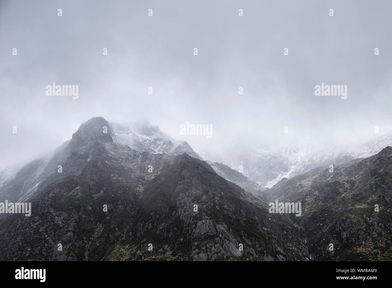 Atemberaubende Moody dramatische Winterlandschaft mountain Bild von schneebedeckten Y Garn in Snowdonia Stockfoto