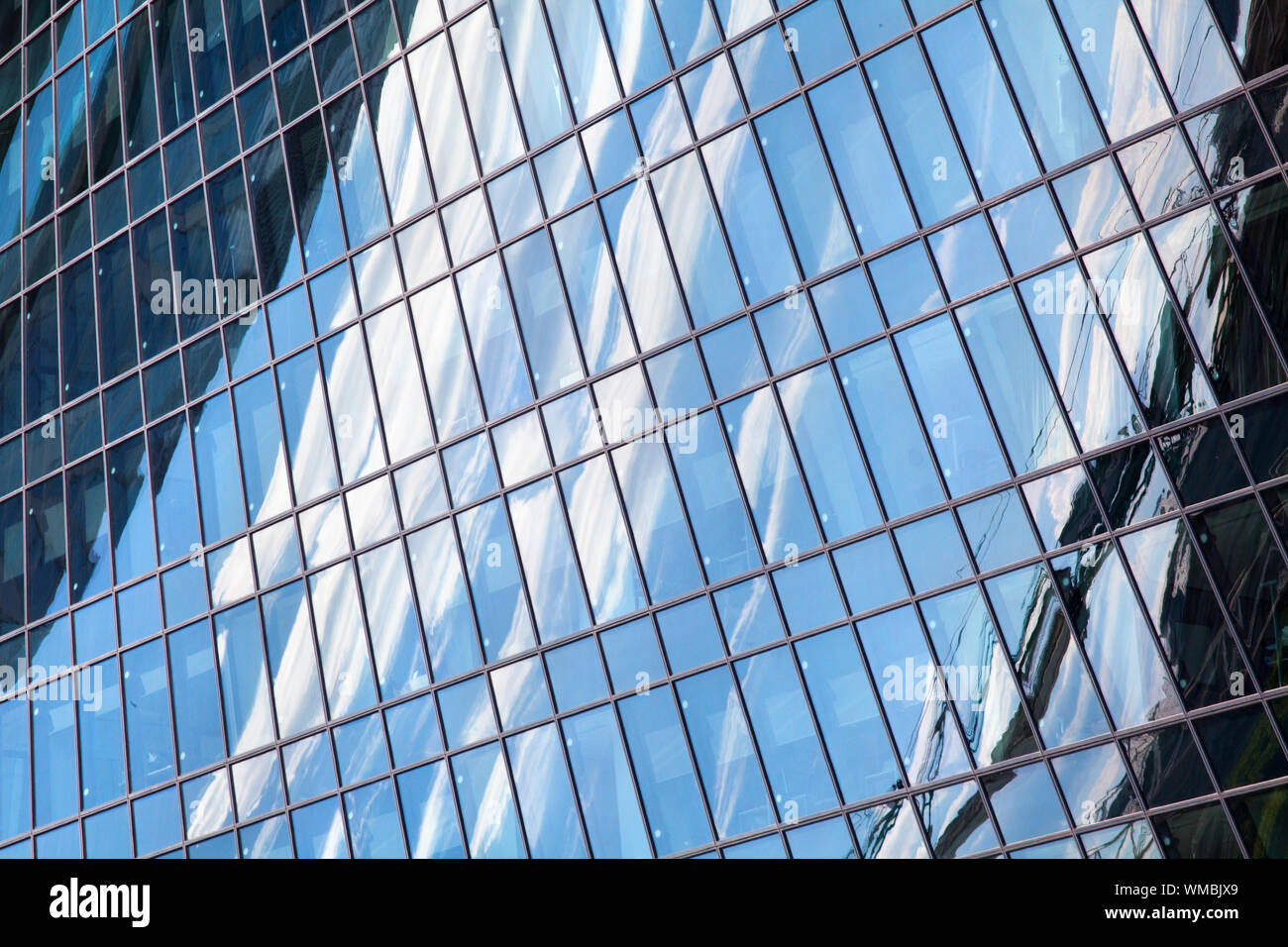 Glas Spiegel skyscraper Wand mit blauem Himmel und weißen Wolken Reflexion Nahaufnahme modernes Business Center anzeigen Financial City District, geometrische Muster Stockfoto