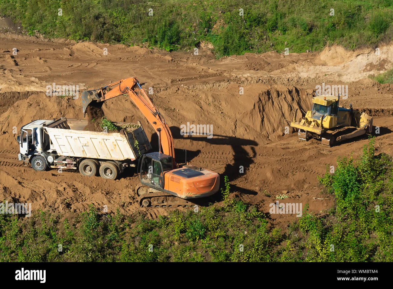 Bagger laden Muldenkipper mit Sand an der Baustelle. Stockfoto