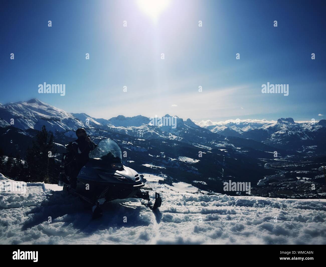 Mann mit dem Schneemobil auf schneebedeckte Berge gegen Sky Stockfoto