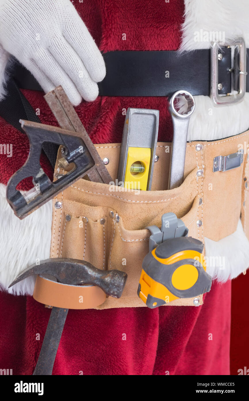 Der Weihnachtsmann trägt ein Werkzeug Riemen vor rotem Hintergrund  Stockfotografie - Alamy