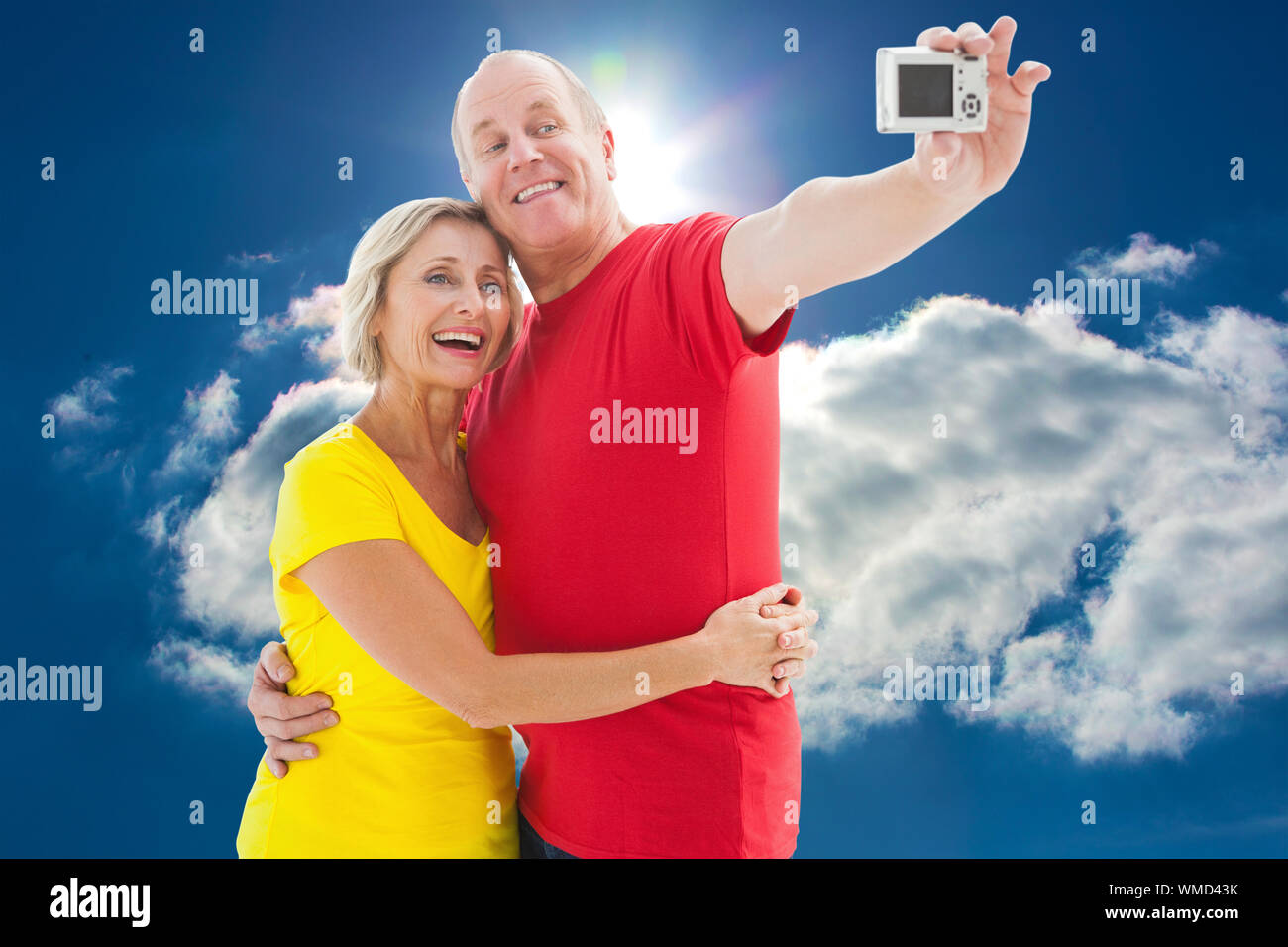 Gerne älteres Ehepaar ein selfie zusammen gegen den blauen Himmel mit Wolken und Sonne Stockfoto