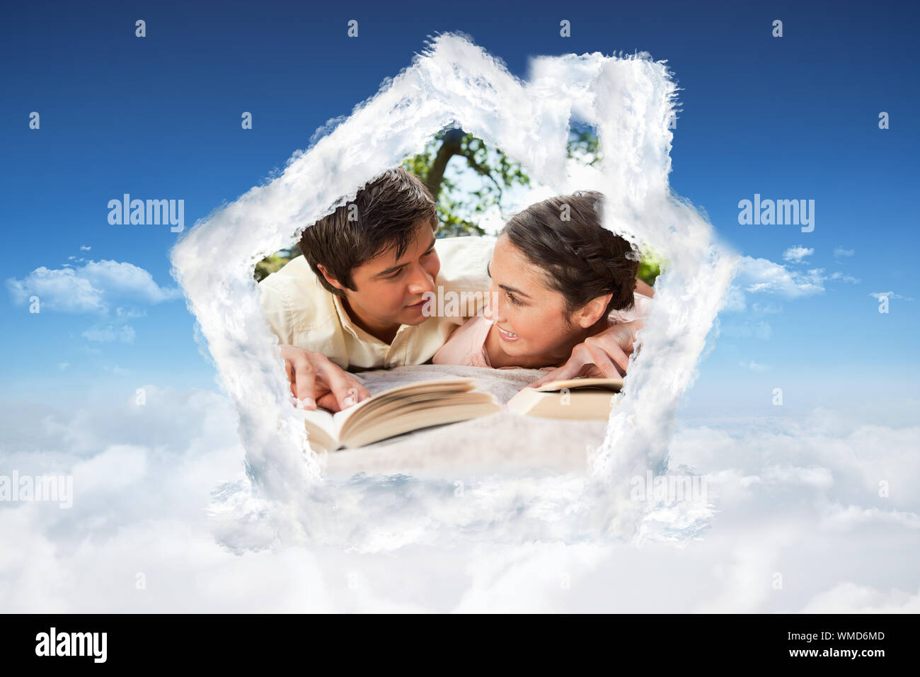 Zwei Freunde, die sich einander beim Lesen der Bücher auf einer Decke gegen den strahlend blauen Himmel über den Wolken Stockfoto
