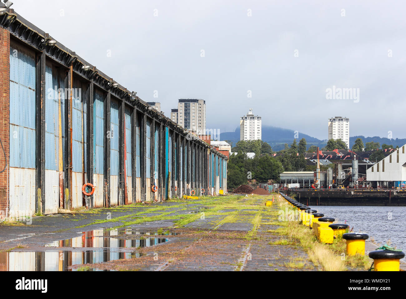 Bleibt von einer leeren Schuppen am King George V Dock, Glasgow, Schottland auf dem Fluss Clyde mit dem hohen Wohnungen von Partick in der Ferne. Stockfoto