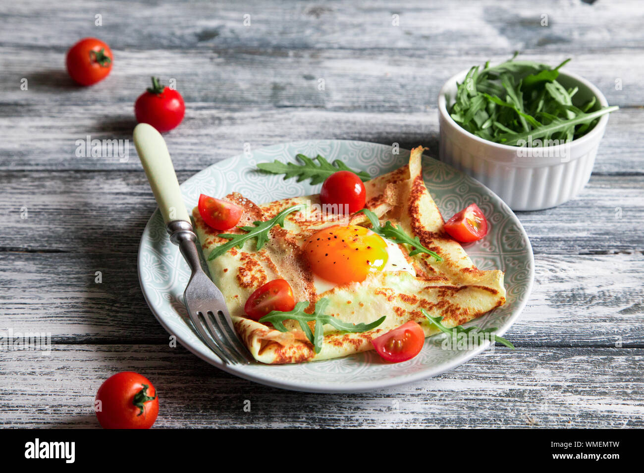 Crepes mit Eiern, Käse, Rucola Blätter und Tomaten. Galette abgeschlossen. Traditionelles Gericht galette Sarrasin Stockfoto