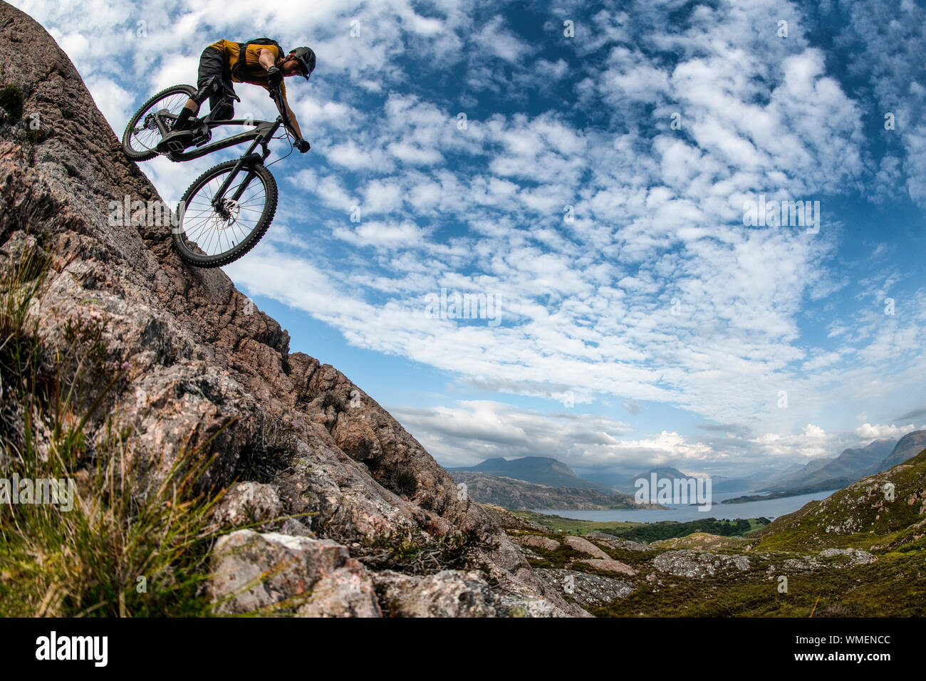 Ein Mann fährt mit einem Mountainbike-Rad eine Felsplatte auf der Halbinsel Applecross im Nordwesten der schottischen Highlands hinunter. Stockfoto