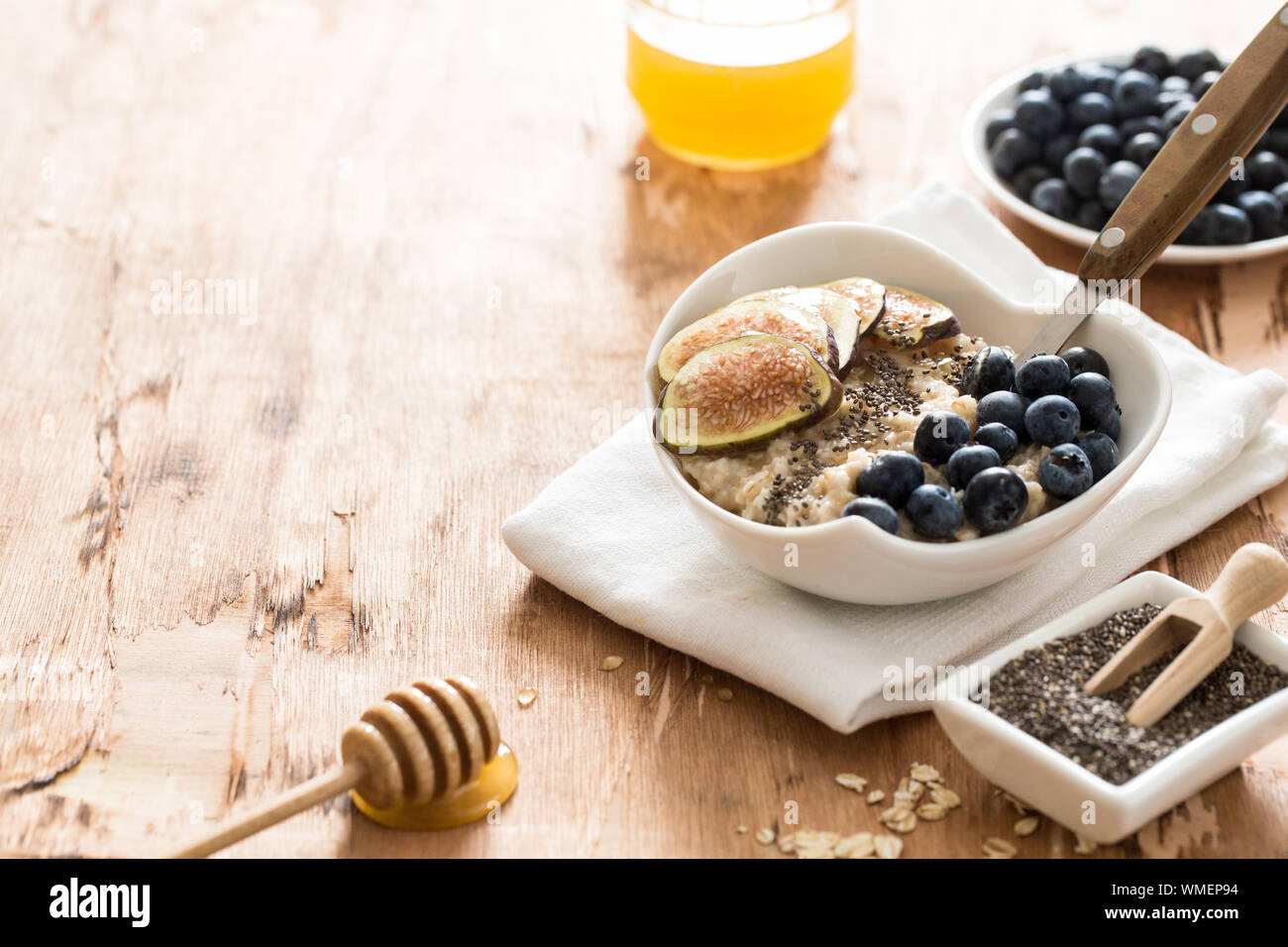 Weiße Schüssel von Hafer Porridge mit Feigen, Blaubeeren und Chia Samen. Gesundes Müsli Frühstück. Stockfoto