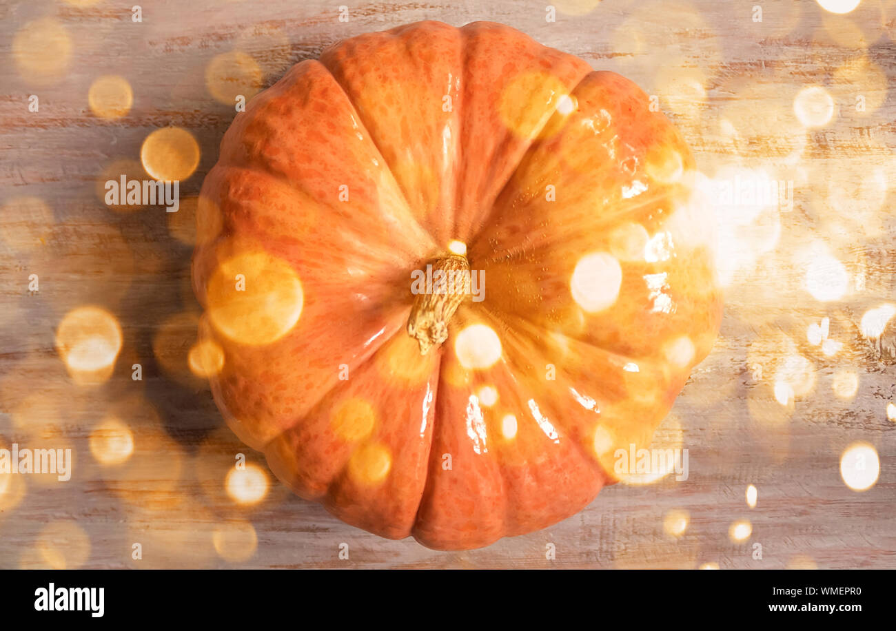 Urlaub Hintergrund der grosse orange Kürbis auf die Holzbretter mit funkelt und Bokeh leuchtet. Feier Konzept. Flach. Stockfoto