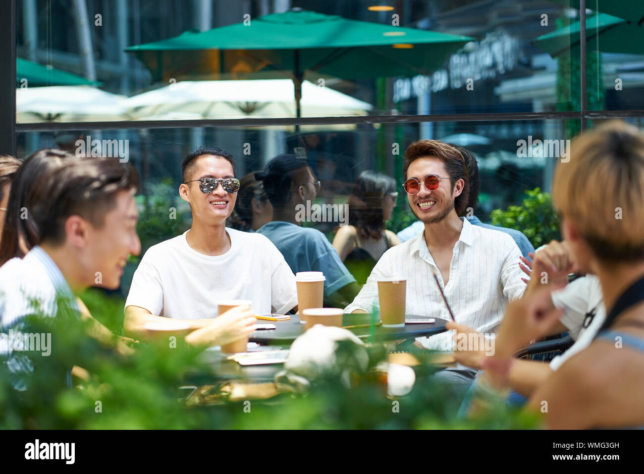 Gruppe der glücklichen jungen asiatischen Erwachsene sitzen im freien Gespräch plaudern und Kaffee trinken Stockfoto