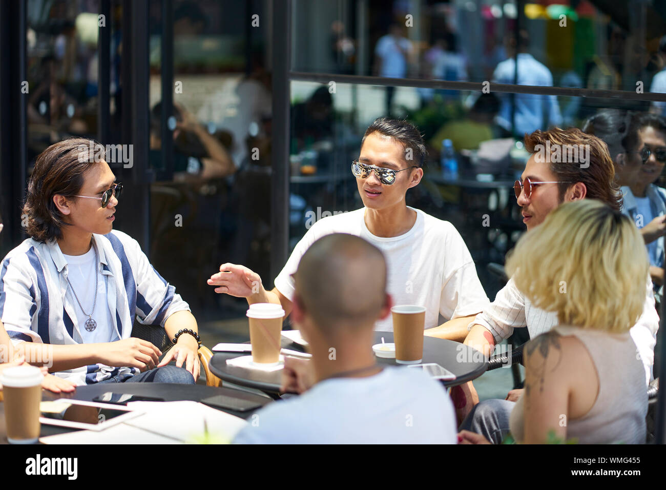 Junge asiatische Studenten in eine Diskussion in der Gruppe an einer im Coffee Shop Stockfoto