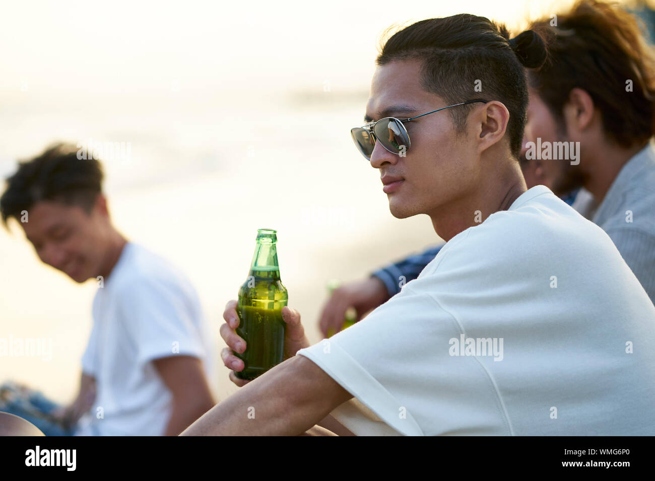 Jungen asiatischen erwachsene Männer sitzen am Strand entspannen und Bier trinken. Stockfoto