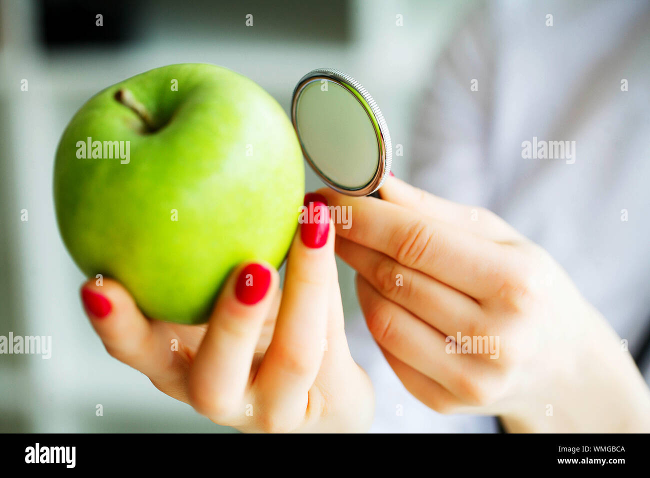 Gesundheit. Das gesunde Essen. Die Ernährungsberaterin hält in den Händen von frischen, grünen Apfel. Frisches Obst und Gemüse auf den Tisch. Gerne Arzt. Hohe Stockfoto