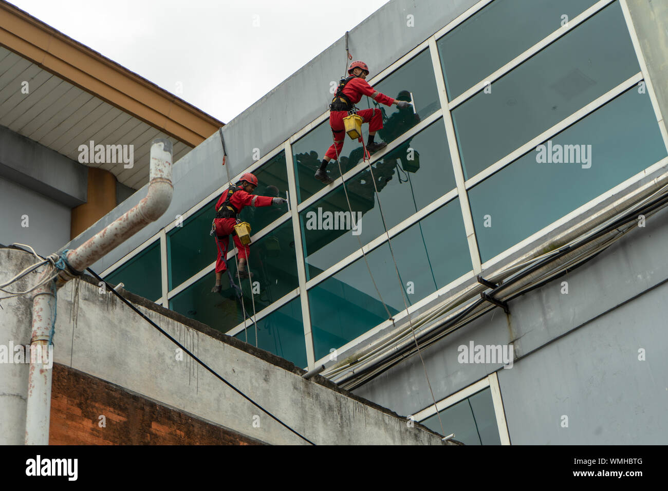 DENPASAR/Bali, Indonesien - 26. AUGUST 2019: Hausmeister oder Reinigung Service waren die Reinigung der Fenster befindet sich auf der Höhe eines mit kompletten safet Gebäude Stockfoto