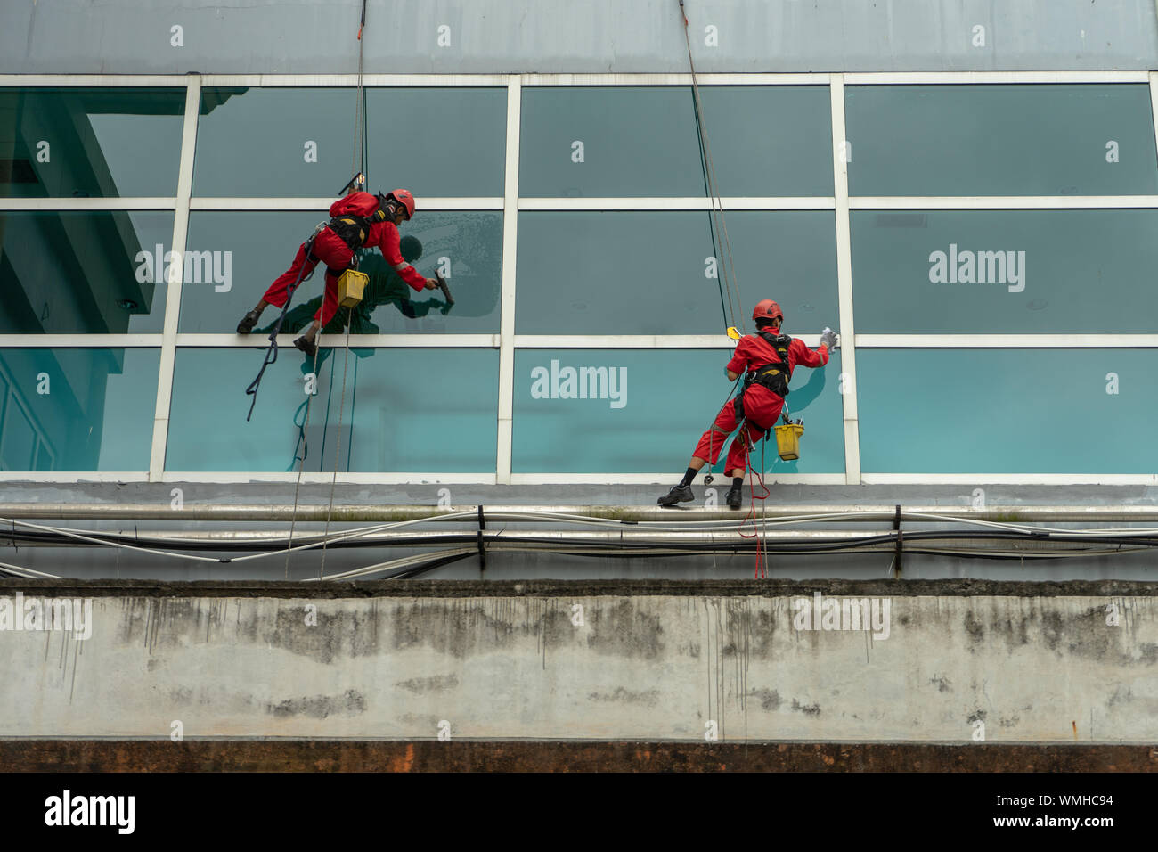 DENPASAR/Bali, Indonesien - 26. AUGUST 2019: Hausmeister oder Reinigung Service waren die Reinigung der Fenster befindet sich auf der Höhe eines mit kompletten safet Gebäude Stockfoto