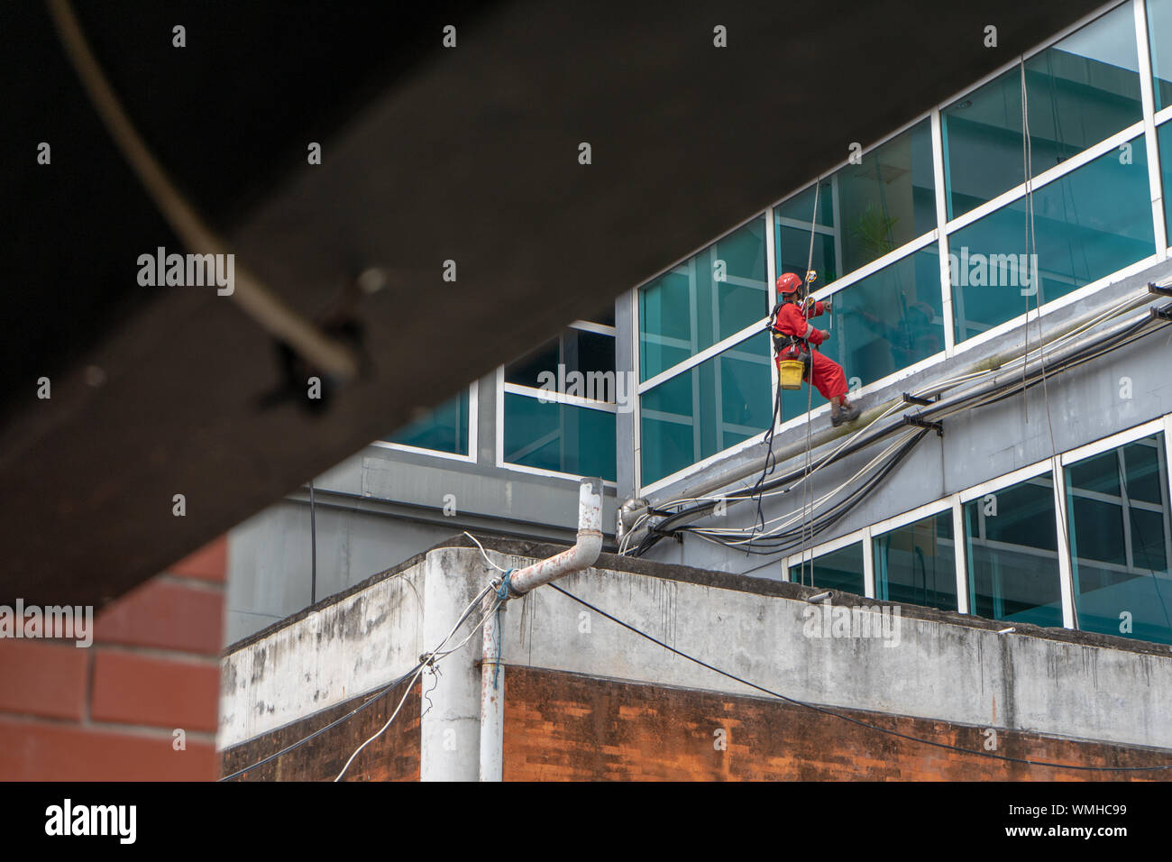 DENPASAR/Bali, Indonesien - 26. AUGUST 2019: Hausmeister oder Reinigung Service waren die Reinigung der Fenster befindet sich auf der Höhe eines mit kompletten safet Gebäude Stockfoto