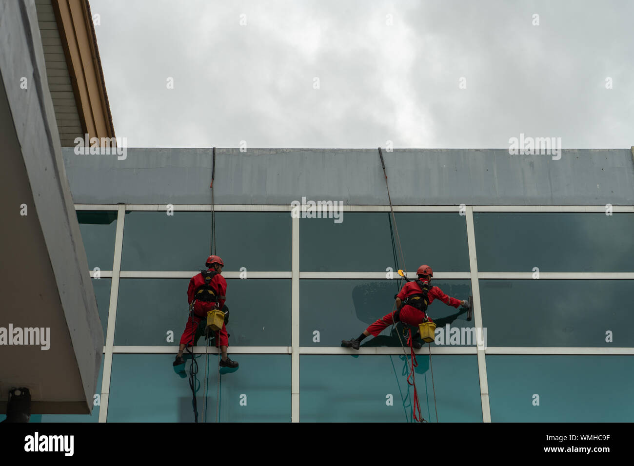 DENPASAR/Bali, Indonesien - 26. AUGUST 2019: Hausmeister oder Reinigung Service waren die Reinigung der Fenster befindet sich auf der Höhe eines mit kompletten safet Gebäude Stockfoto