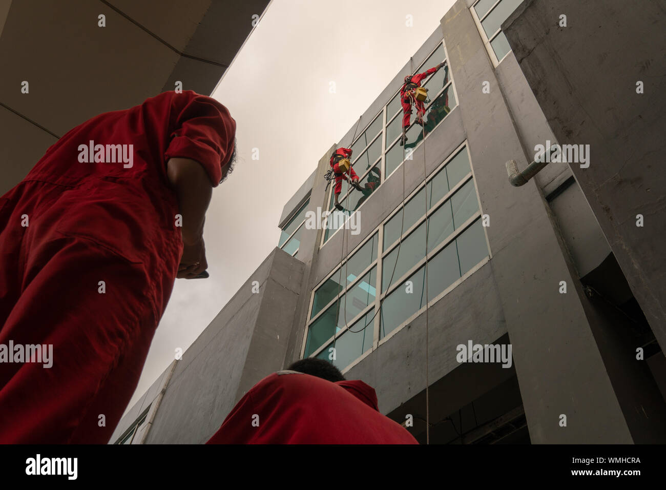 DENPASAR/Bali, Indonesien - 26. AUGUST 2019: Hausmeister oder Reinigung Service waren die Reinigung der Fenster befindet sich auf der Höhe eines mit kompletten safet Gebäude Stockfoto