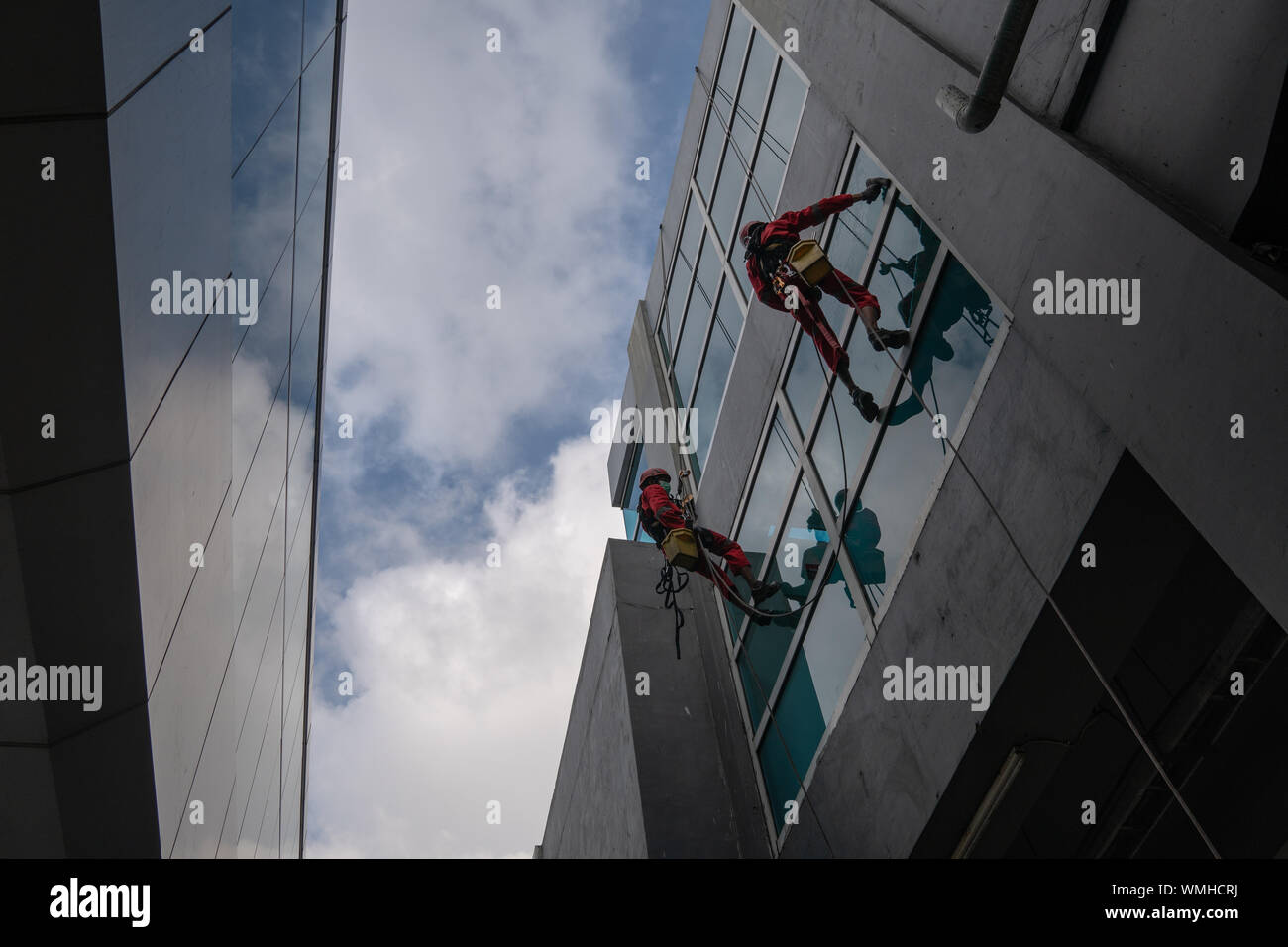 DENPASAR/Bali, Indonesien - 26. AUGUST 2019: Hausmeister oder Reinigung Service waren die Reinigung der Fenster befindet sich auf der Höhe eines mit kompletten safet Gebäude Stockfoto