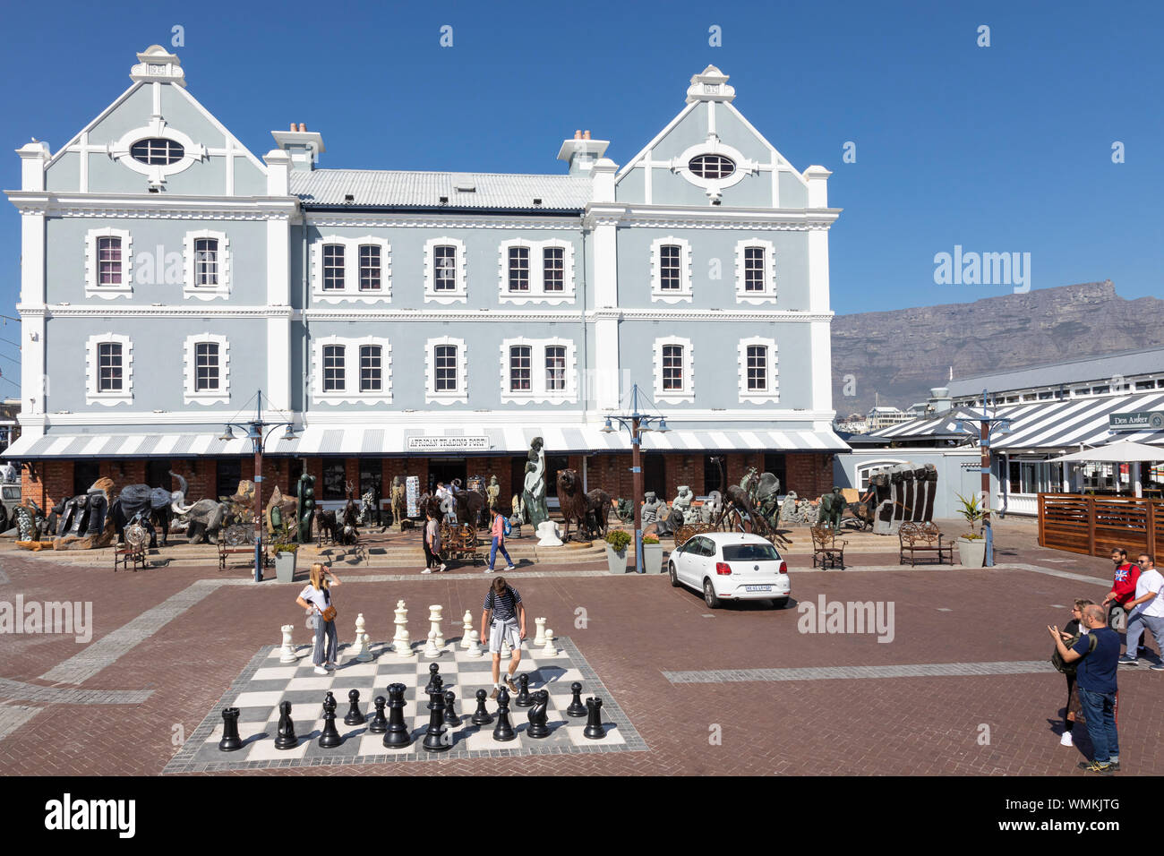 Touristen bewundern die Schachbrett im Freien vor der afrikanischen Handel Hafen mit seiner Darstellung afrikanischer Skulptur, V&A Waterfront, Kapstadt, Sout Stockfoto