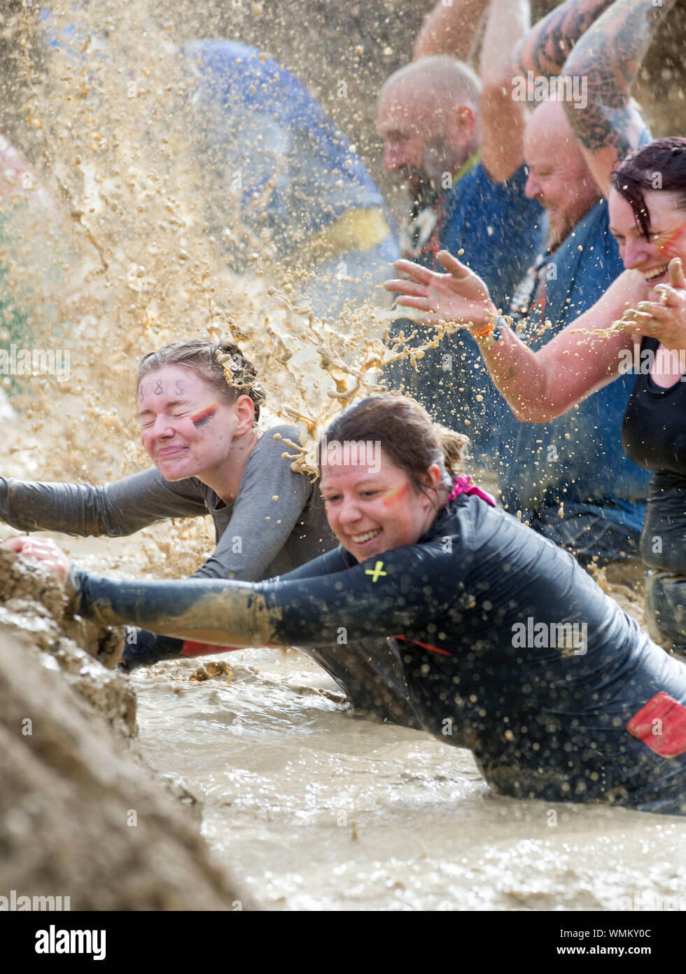 Konkurrenten verhandeln die 'Mud Mile' Hindernis im harten Mudder Ausdauer Event im Badminton Park, Gloucestershire, Großbritannien Stockfoto