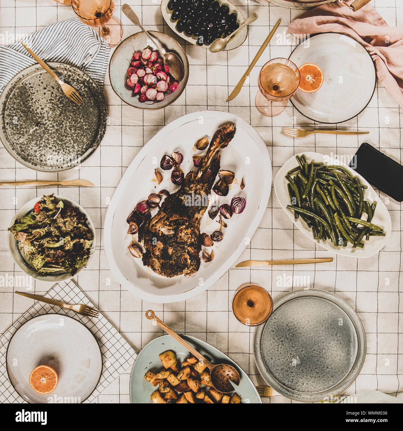 Familie, Freunde treffen zum Abendessen. Flachbild-lay von gebratene Lammschulter, Salate, gebackenem Gemüse, Snacks, Brot, Rose Wein und blühenden Mimosen Zweige o Stockfoto