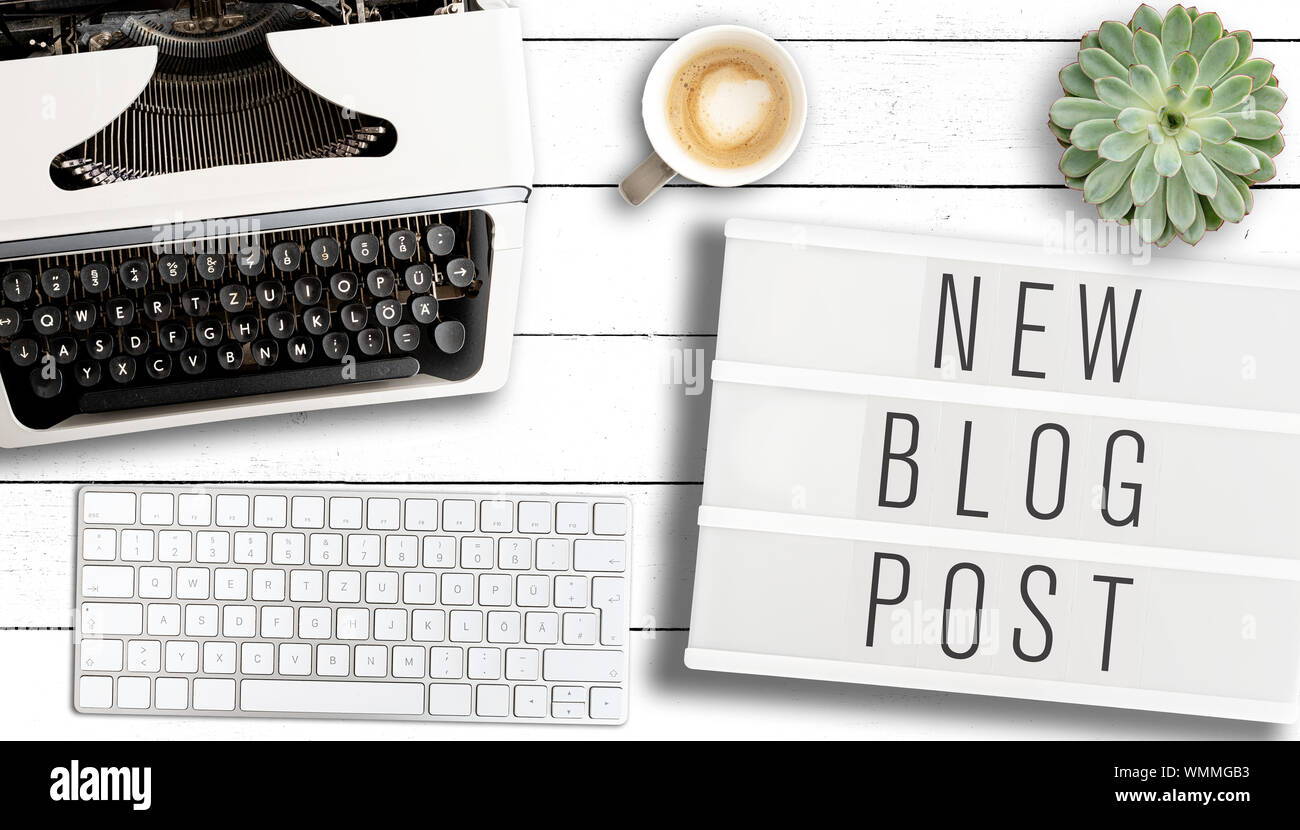 Blogging Konzept, Ansicht von oben Text neuen Blog-eintrag auf Leuchtkasten auf Tabelle mit alten Schreibmaschine, Computer Tastatur und Tasse Kaffee Stockfoto