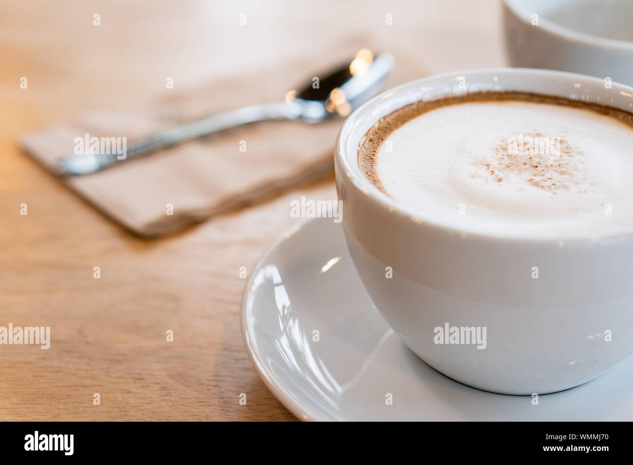 Heißer Kaffee, weiße Tassen, Teller, Löffel und Gewebe alle auf dem Holztisch. Stockfoto