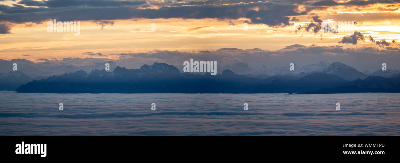 Blick auf die Alpen bei Sonnenaufgang, im Vordergrund Genfer See bewölkt Stockfoto
