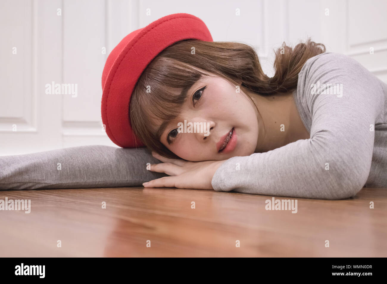 Porträt der jungen Frau mit Red Hat Liegend auf Parkett Stockfoto