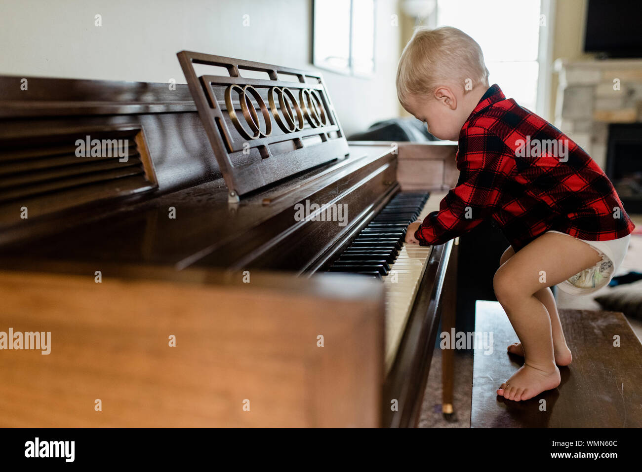 Baby boy in Windel steht auf der Werkbank Klavier spielen zu Hause Stockfoto