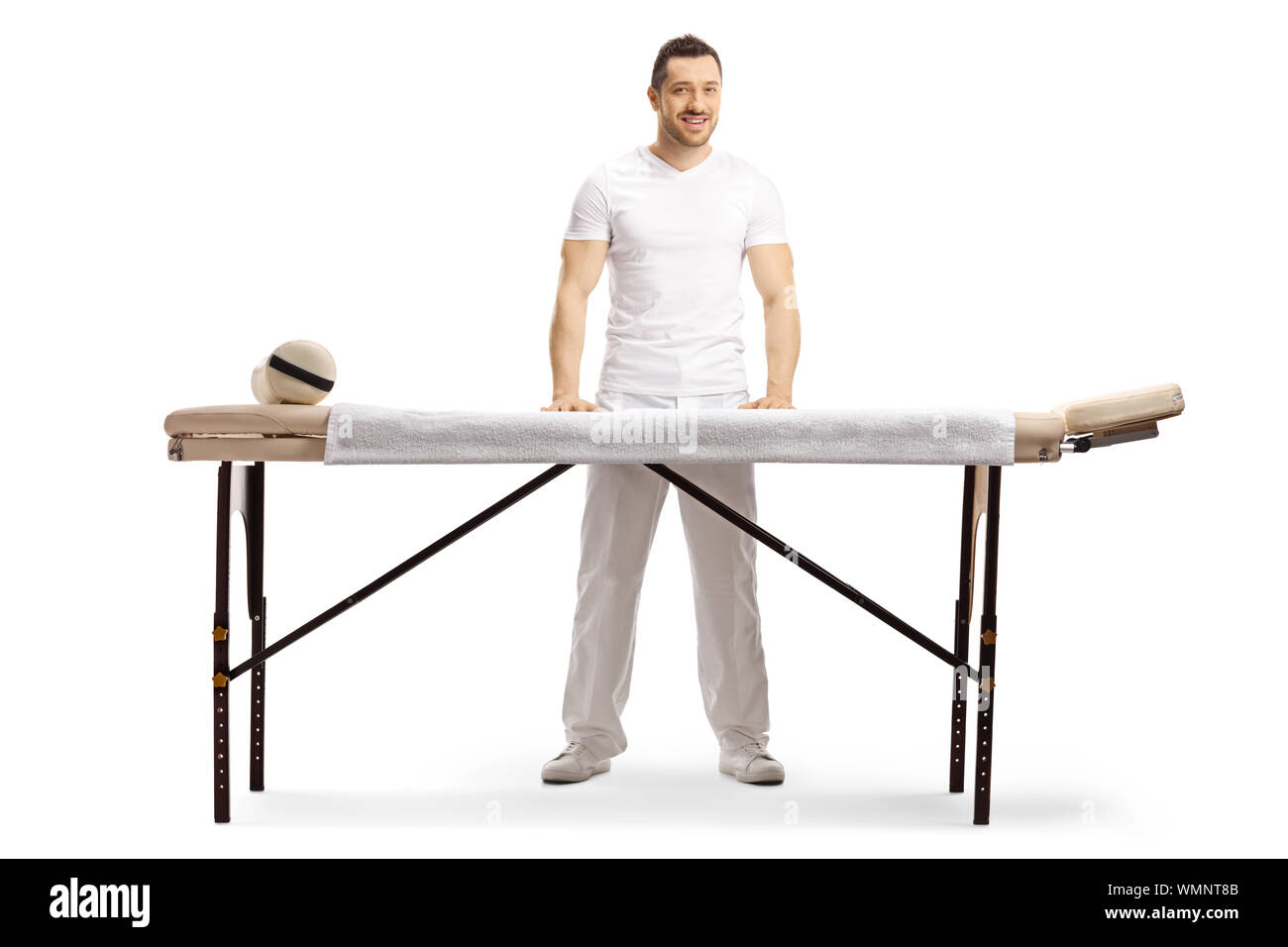 In voller Länge Porträt einer männlichen Masseur hinter einer professionellen Massage Bett auf weißem Hintergrund stehend Stockfoto