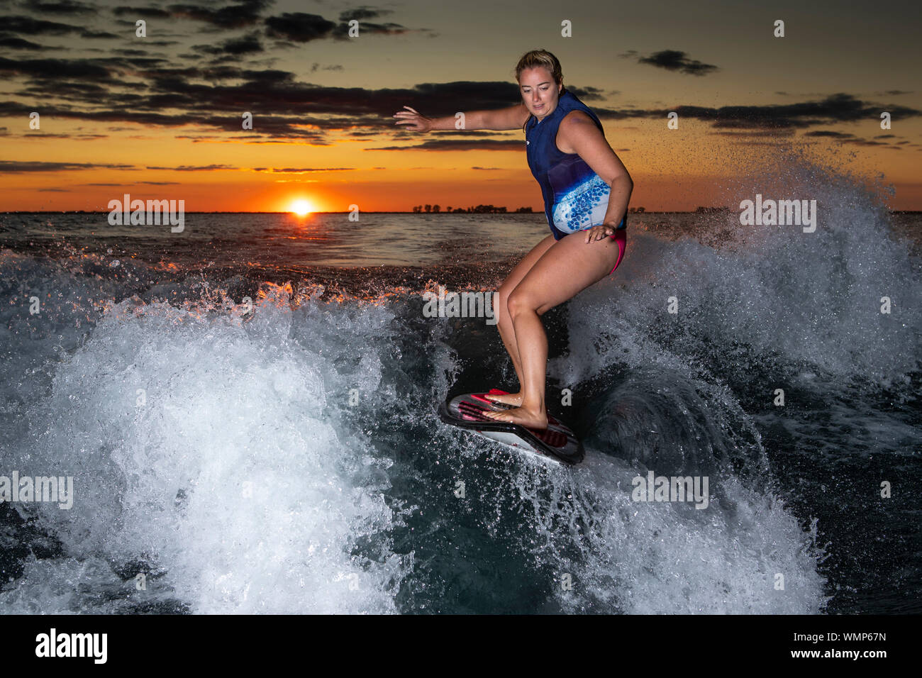 Ein Mädchen surfen auf einem Boot wake bei Sonnenuntergang. Stockfoto