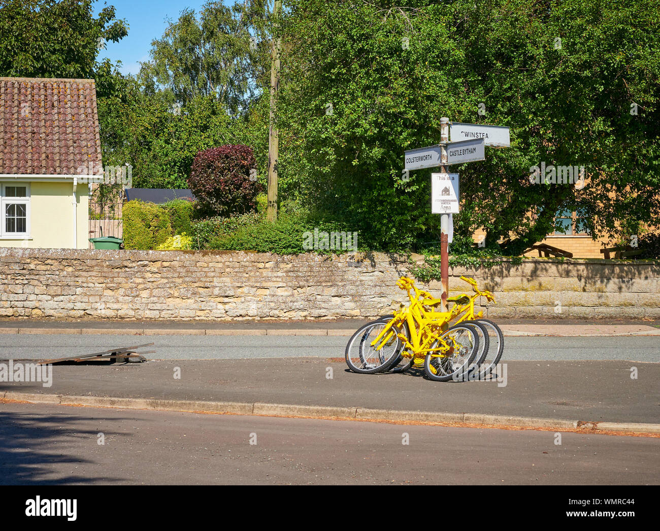 Gelb lackiert recycelt Fahrräder, gegen ein Wegweiser in Swayfield, Lincolnshire in Bereitschaft für den Bourne, Kreislauf Festival Stockfoto