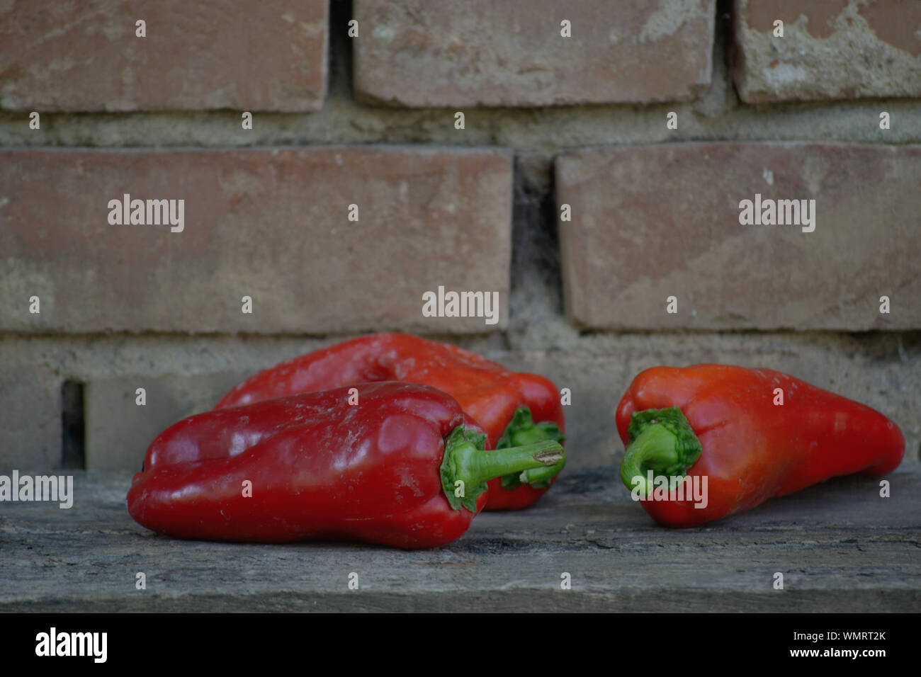 Paprika auf alten hölzernen Brett gegen alte Mauer Stockfoto