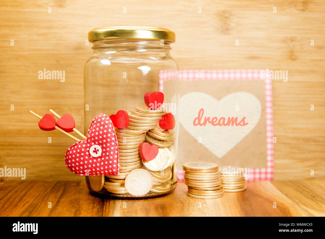 Geld sparen für Träume Konzept. Süße Herz und goldenen Münzen auf Glas. Deko Idee. Stockfoto