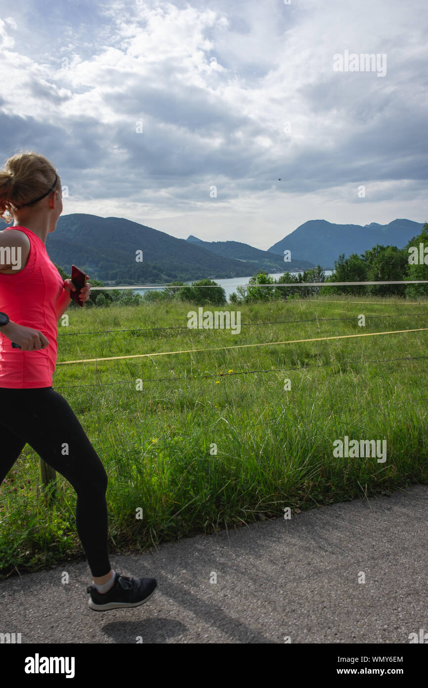 Passende Frau verläuft entlang Schmutz weg in schwarze Leggings und rosa Top Stockfoto