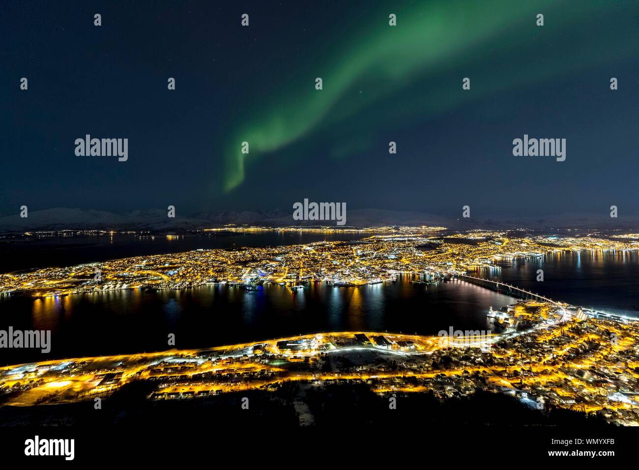 Beleuchtete Stadt und Aurora borealis über Fjellheisen, Tromso, Norwegen Stockfoto