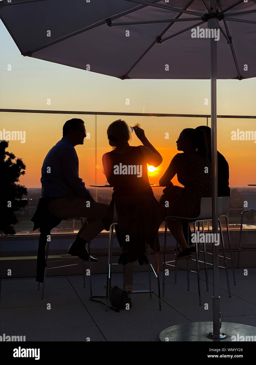 Vier Personen Sundowner auf der Terrasse bei Sonnenuntergang, Deutschland Stockfoto