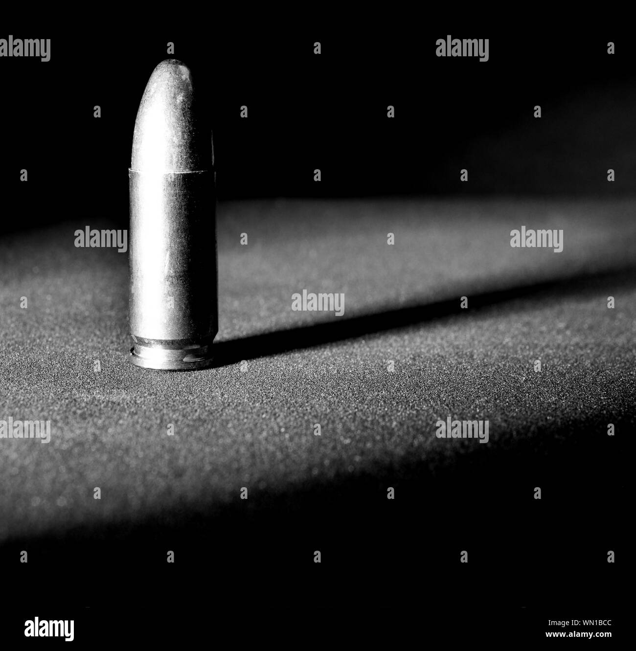 Einen einzigen Ständigen 9 mm bullet mit dramatischen Seite Licht und Schatten in Schwarz und Weiß Stockfoto
