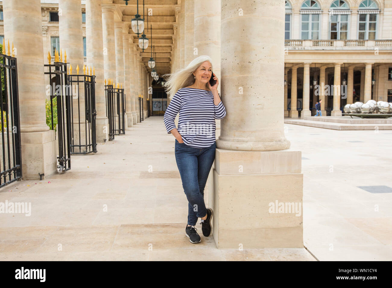 Frau am Telefon durch Spalten des Palais Royal in Paris, Frankreich Stockfoto