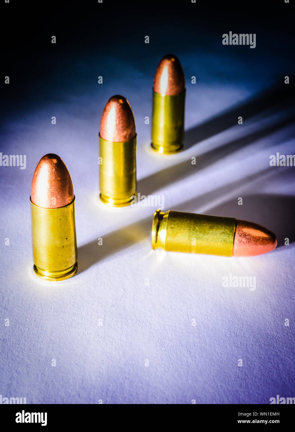 Drei ständigen 9 mm Kugeln neben einem gefallenen bullet mit dramatischen Seite Licht, Schatten und Farbe Stockfoto