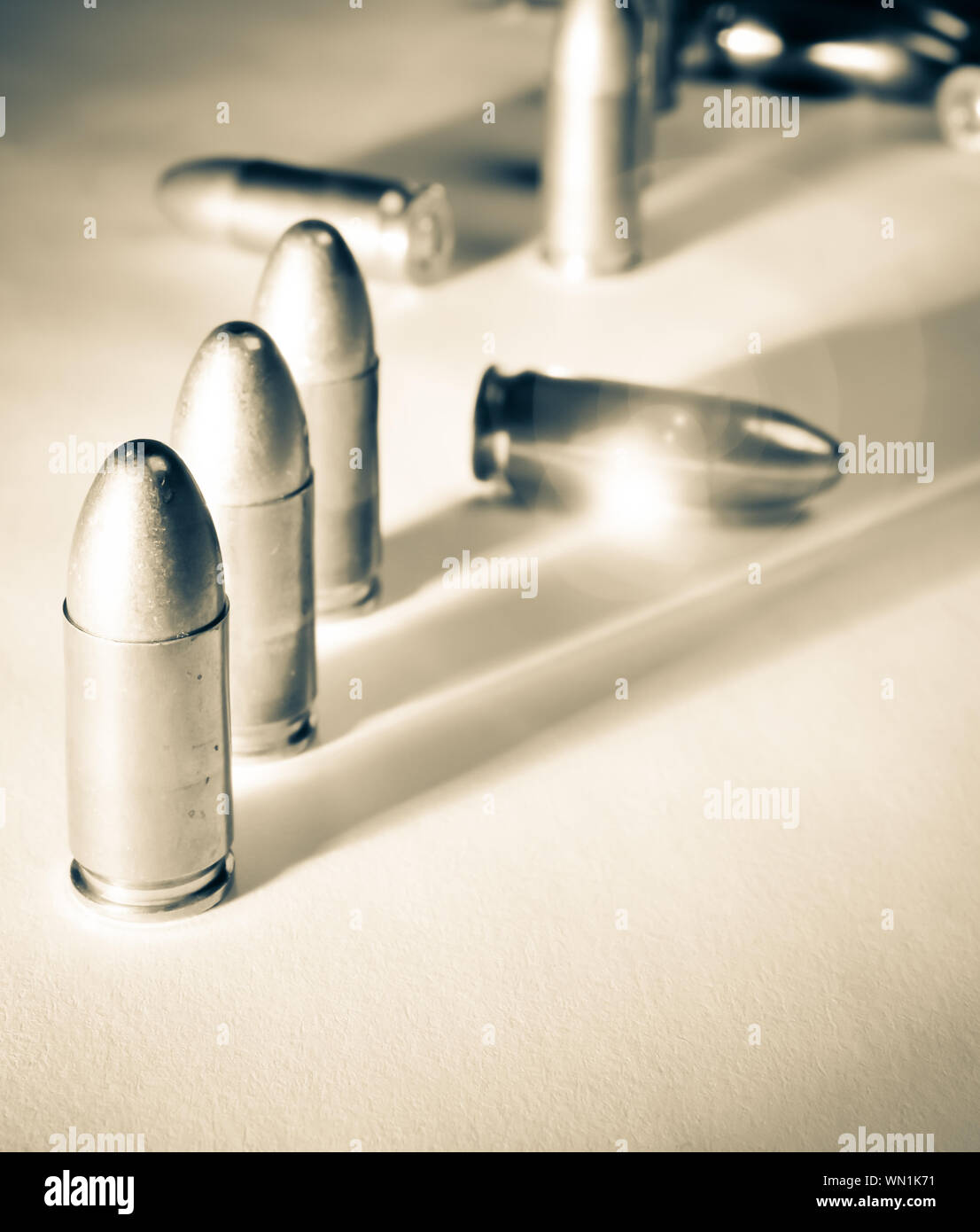 Drei ständigen 9 mm Kugeln neben zwei gefallenen Kugeln mit dramatischen Seite Licht und Sonne - Flair in warmen Ton Schwarz und Weiß Stockfoto