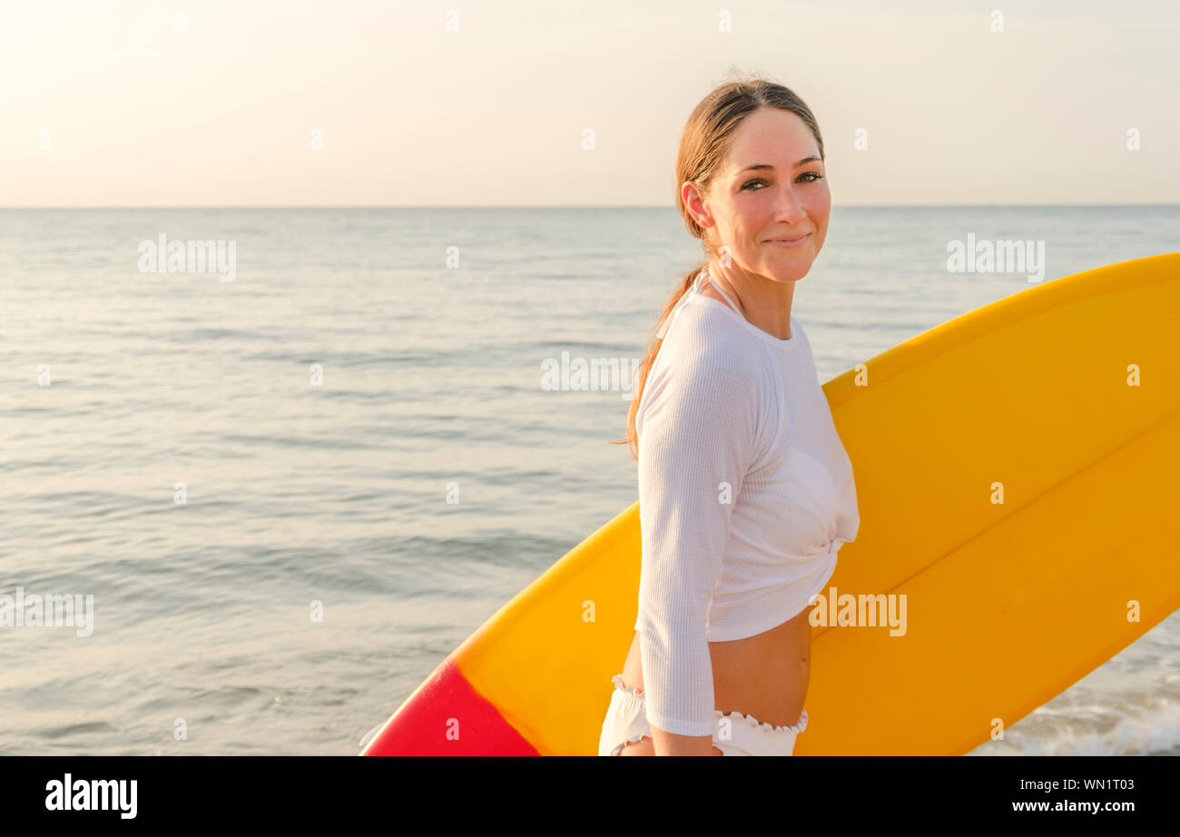 Frau tragen weiße Bikini surfboard Durchführung am Strand Stockfoto