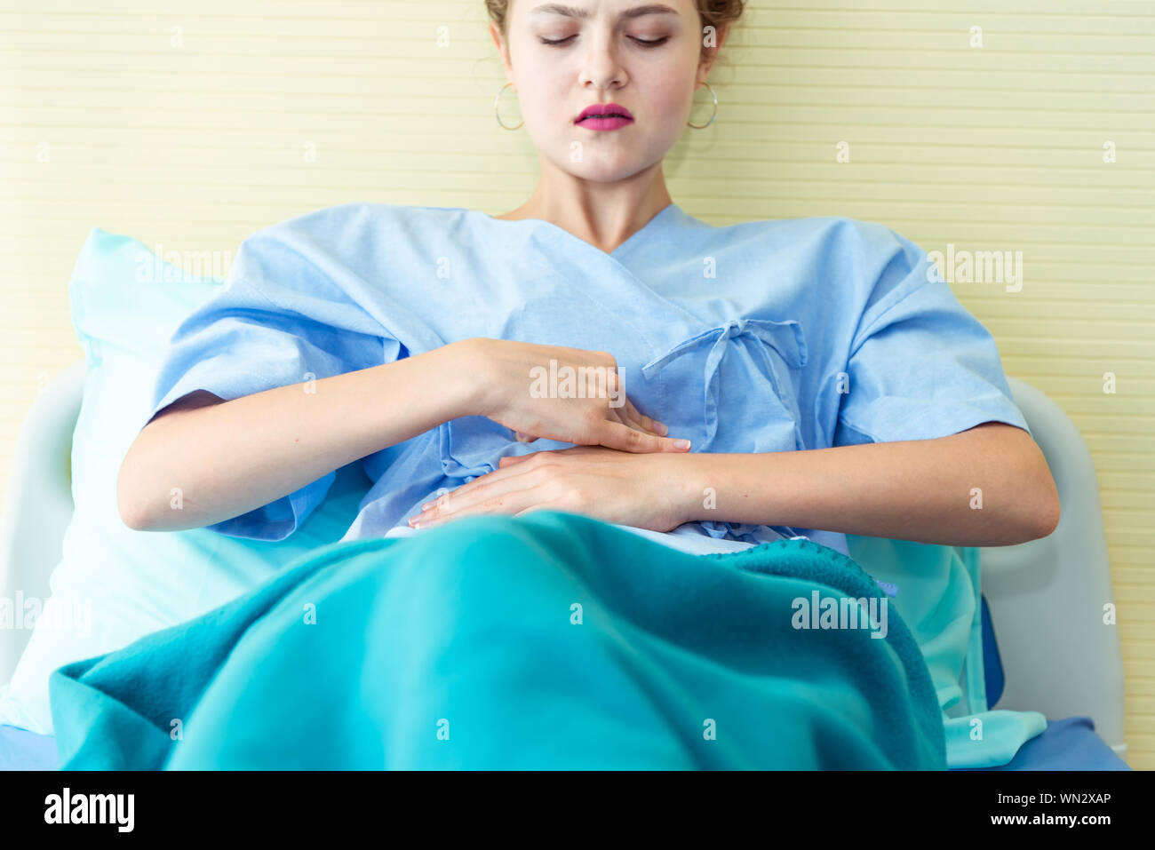 Junge weibliche Patienten krank mit Magenschmerzen, Menstruation Krämpfe, Bauchschmerzen, Lebensmittelvergiftung auf dem Bett im Krankenhaus, während sie darauf warten, die physische Arzt e Stockfoto