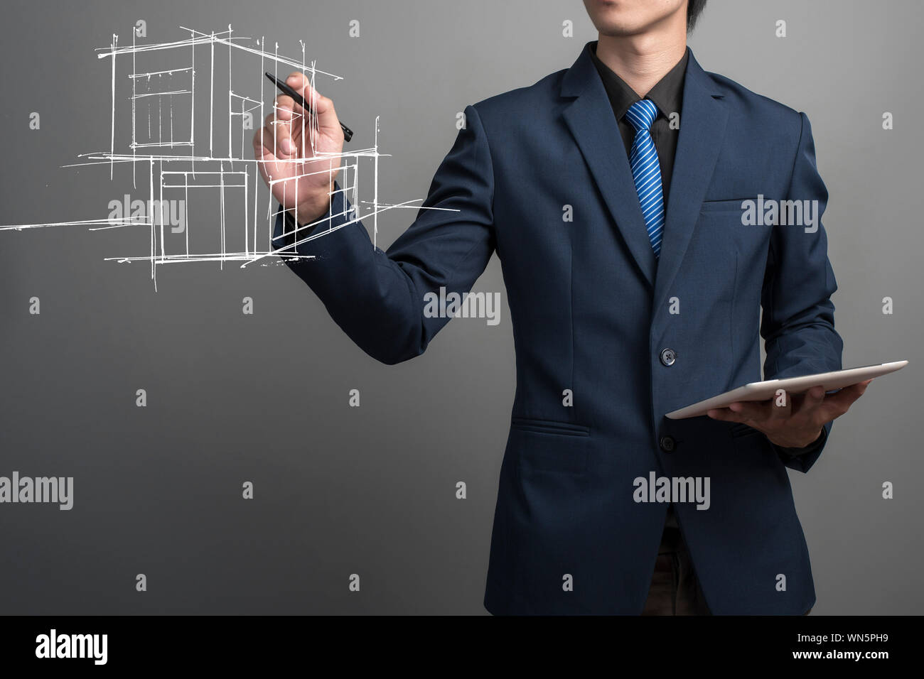 Digital zusammengesetzten Bild des Geschäftsmannes, der Wohnungsbau Während die Tablette gegen grauer Hintergrund Stockfoto