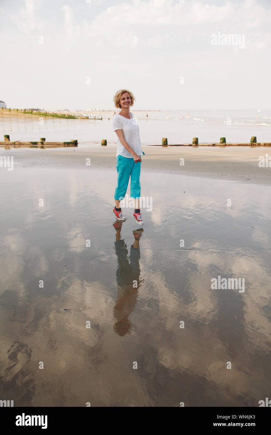 Portrait von lächelnden Mitte der erwachsenen Frauen zu Fuß am Strand gegen Sky Stockfoto