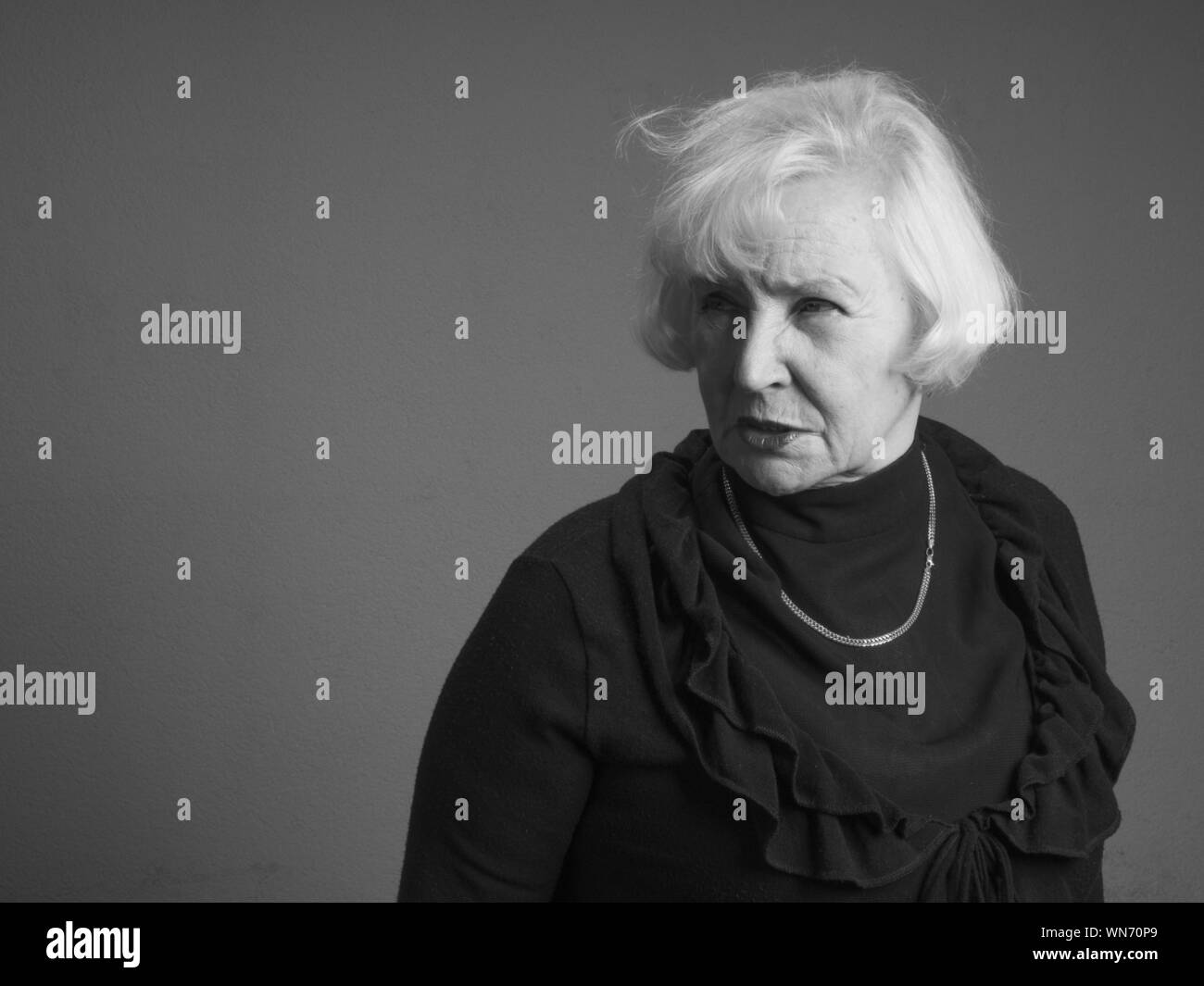 Ältere Frau gegen grauer Hintergrund Stockfoto