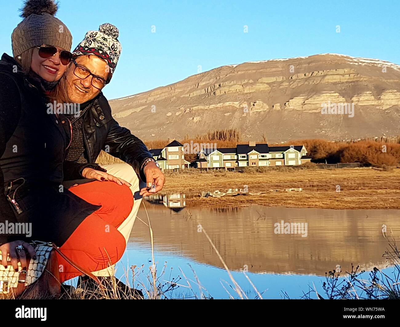Portrait von lächelnden Reifes Paar Hockend von Argentino See gegen Berg Stockfoto